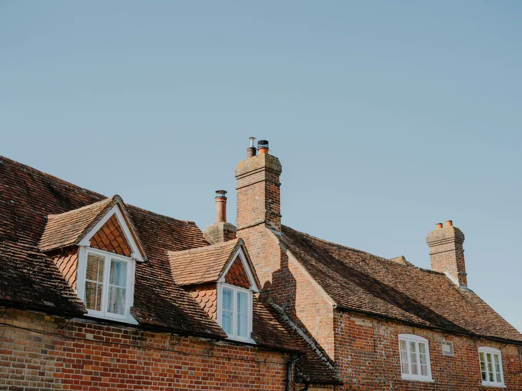 Brick houses with dormer windows and pitched tiled roofs under a blue sky